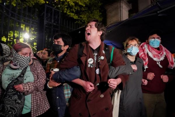 Protestors l<em></em>ink arms as other police officers enter the campus of Columbia University