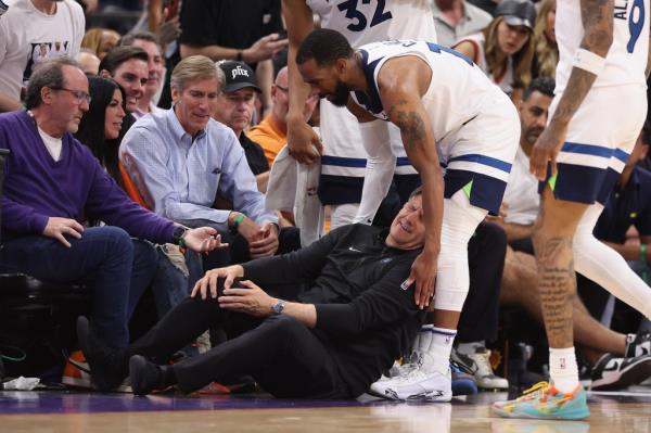 Tiimberwolves head coach Chris Finch grabs his right knee after getting hurt during a game against the Suns on Sunday.