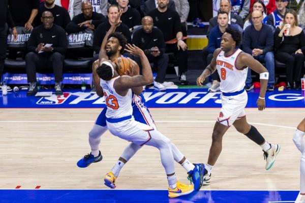 Mitchell Robinson #23 of the New York Knicks draws a foul as Joel Embiid #21 of the Philadelphia 76ers drives into him